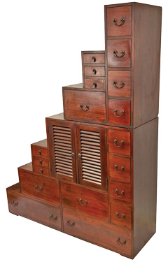 Japanese Step Tansu composed of two sections having 19 drawers and two doors. The top half can be flipped to rest on the base, creating a flat surface. Originally used as steps to access a loft area. Probably cypress, ca. 1950s.